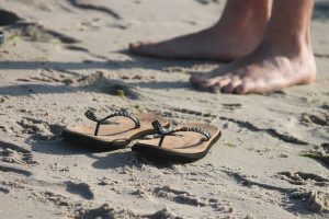 Sandalen und nackte Füße am Strand